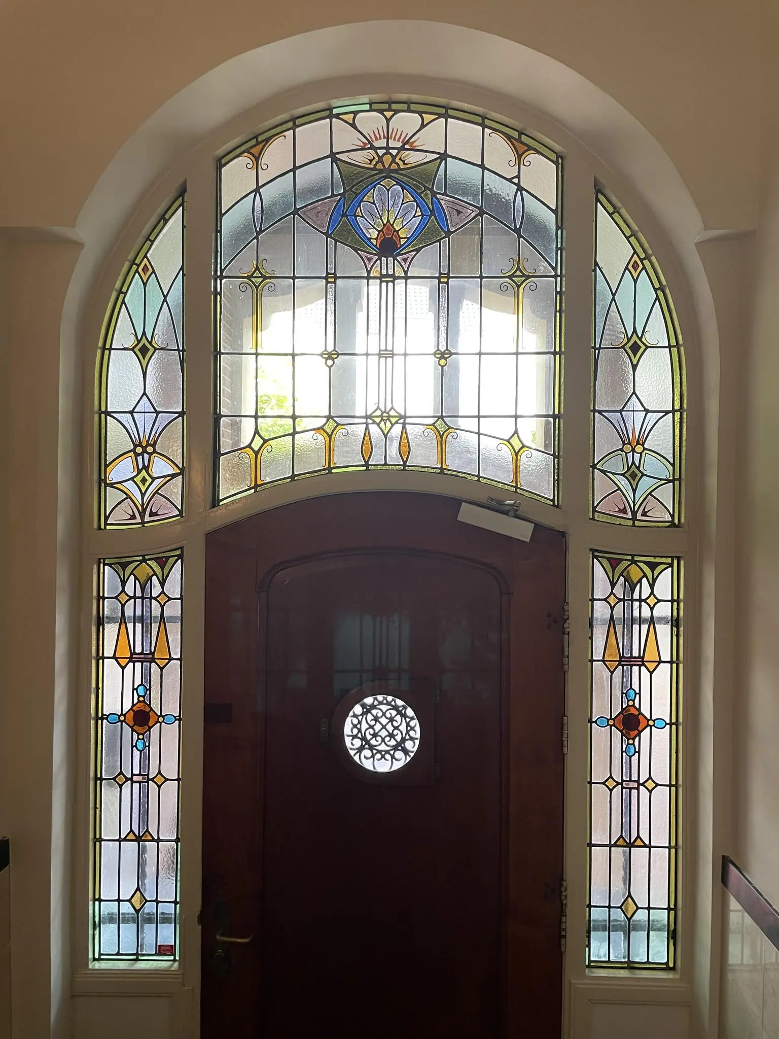 Houten voordeur met kleurrijk glas-in-loodraam in jugendstil-stijl aan de Oranje Nassaulaan.